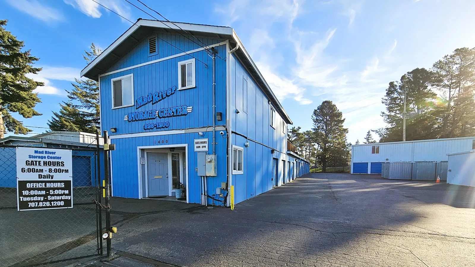 Mad River Storage Center's blue two-story office in McKinleyville, CA, with hours posted at the gate